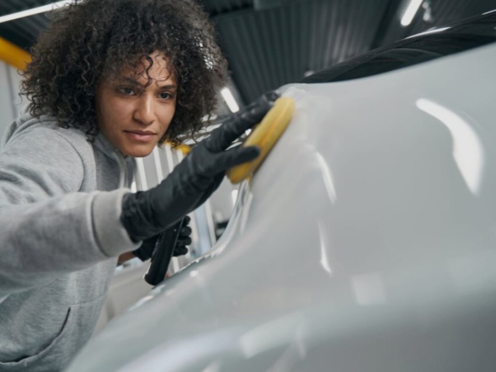 Profissional aplicando produto de cristalização na pintura de um carro branco